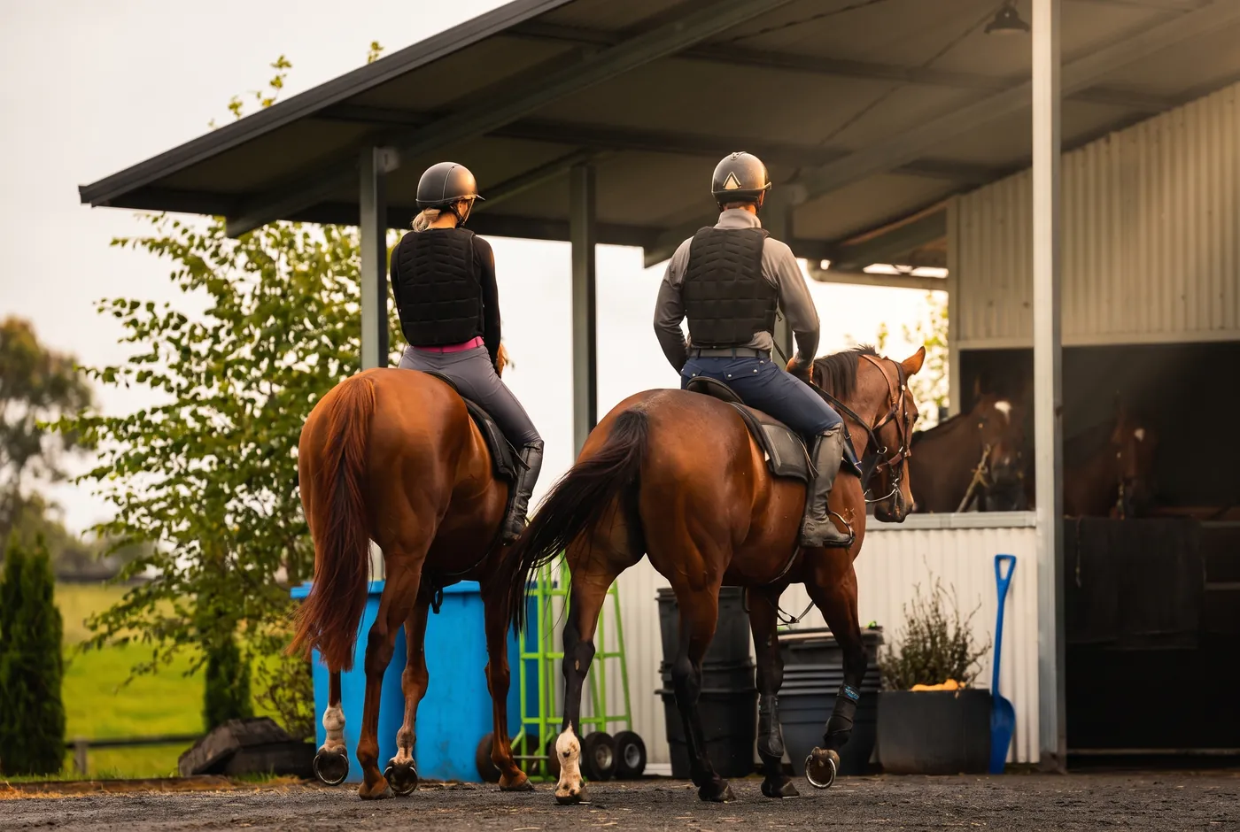 Riders on horseback outside an Elite Equine stable block